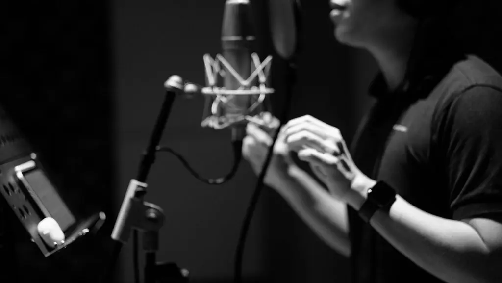 Independent Christian artist recording vocals in a studio with a large-diaphragm mic and pop filter